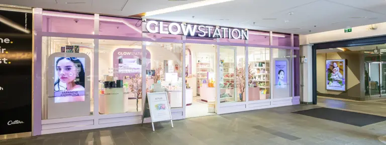GLOWSTATION kosmetiikkakaupan lasinen, vaaleanpunainen julkisivu neon-tekstillä ja sisällä hyllyillä tuotteita.